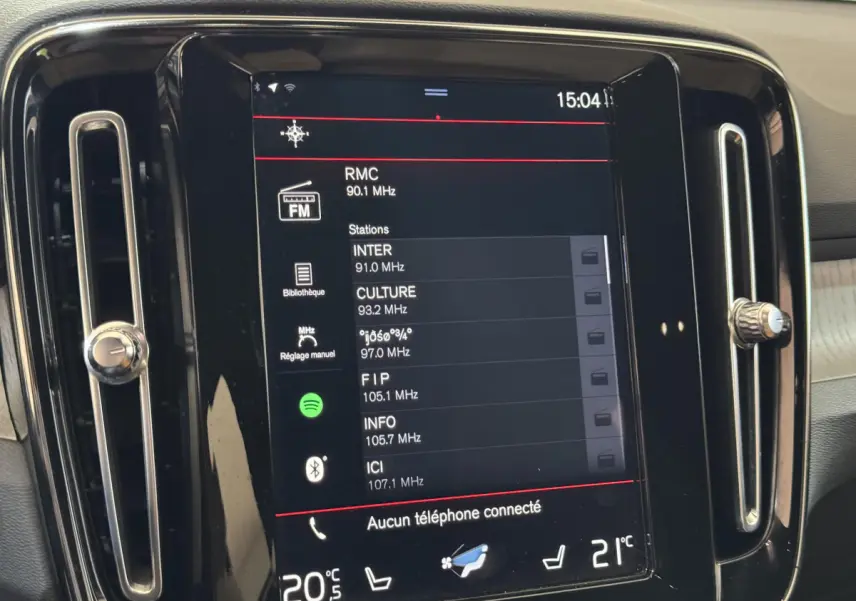 Écran tactile central du tableau de bord du Volvo XC40 noir, affichant les stations radio FM.