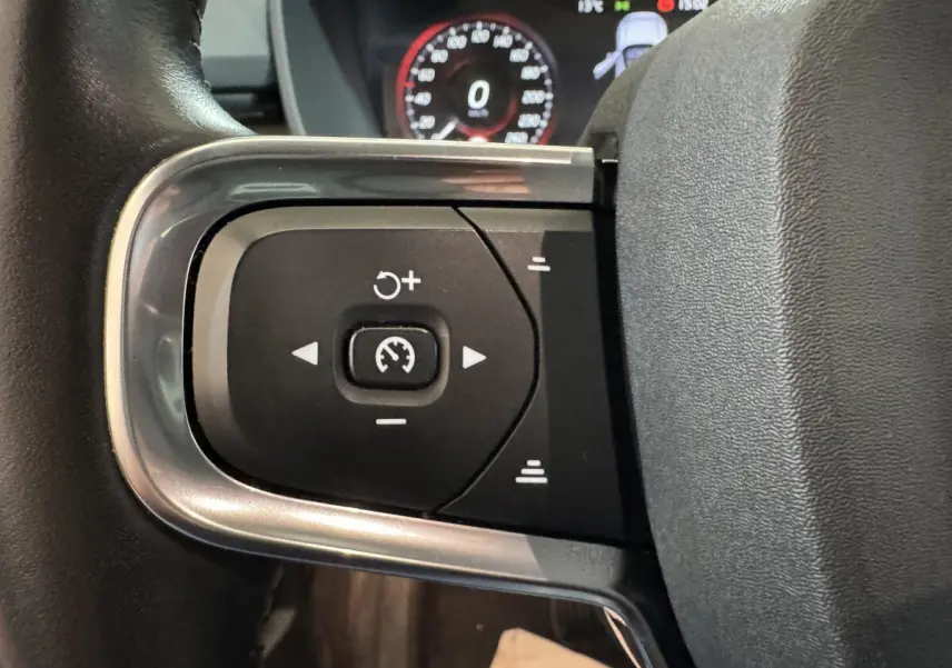 Gros plan sur les commandes de régulateur de vitesse au volant cuir noir du Volvo XC40 Recharge T5 2021.