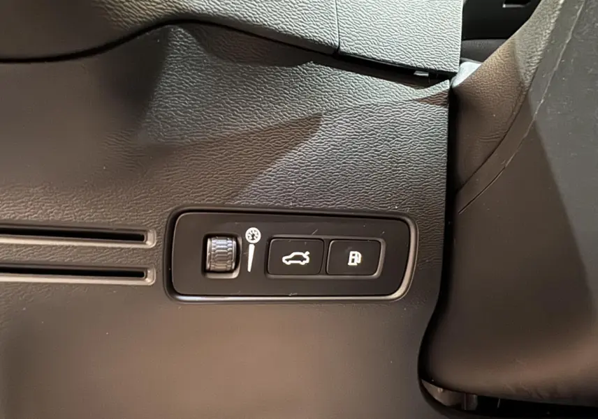 Gros plan sur les commandes d'ouverture du coffre et de la trappe à carburant du Volvo XC40 noir, intérieur côté conducteur.