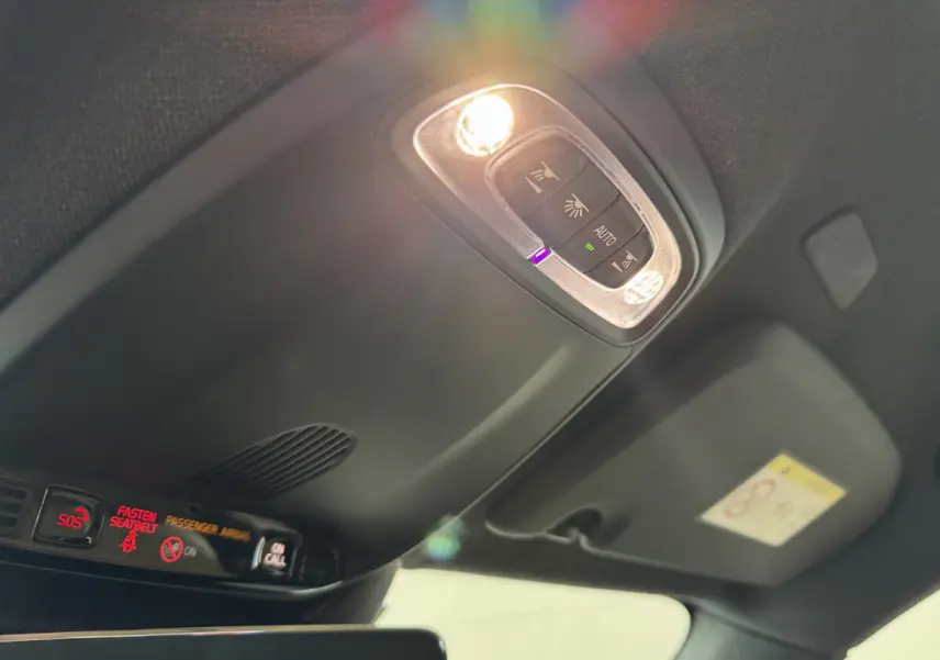 Plafonnier intérieur allumé avec commandes et affichages rouges, vue en contre-plongée dans un Volvo XC40 noir.