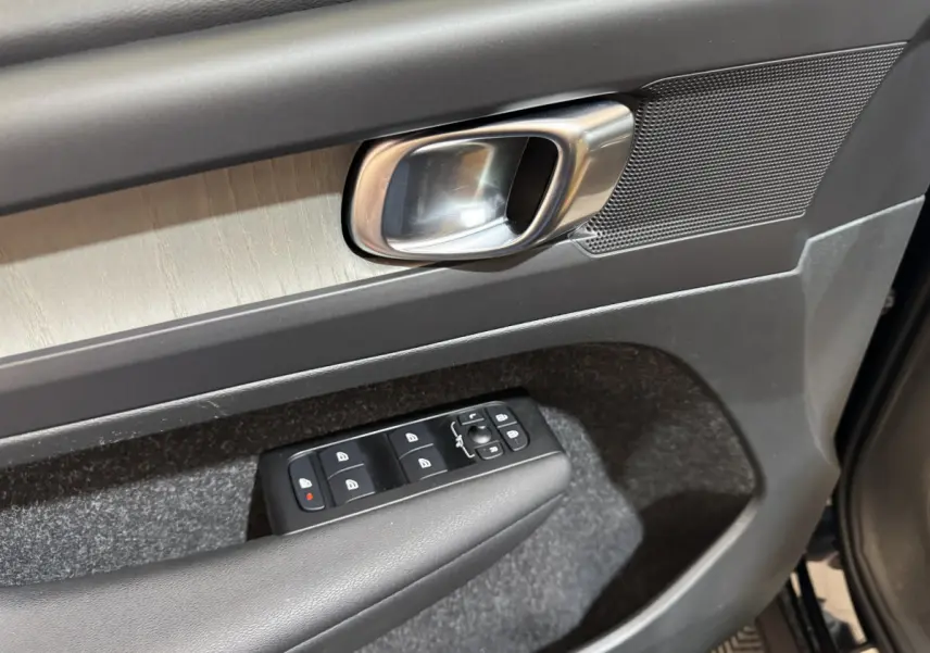 Gros plan sur la porte côté conducteur du Volvo XC40 noir, avec poignée alu et commandes électriques des vitres.