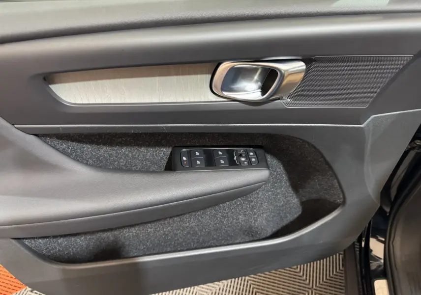 Gros plan sur la porte avant gauche noire du Volvo XC40 Recharge T5, avec commandes électriques et poignée alu.