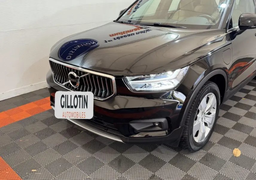 Vue 3/4 avant droit d’un Volvo XC40 Recharge T5 noir, avec calandre chromée et phares LED allumés.