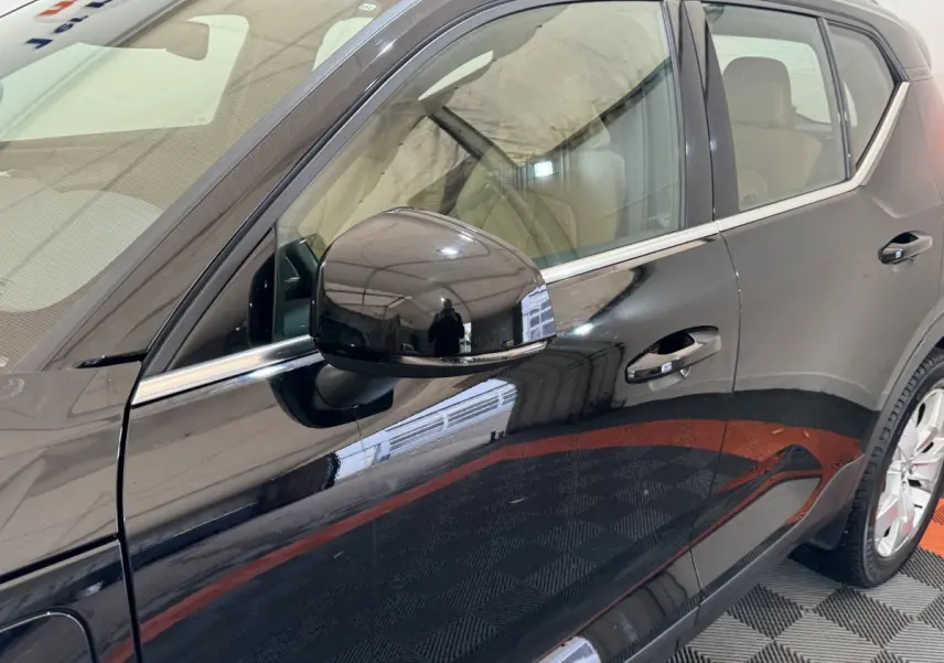 Vue côté gauche rapprochée du Volvo XC40 noir, mettant en valeur la portière et le rétroviseur extérieur brillant.