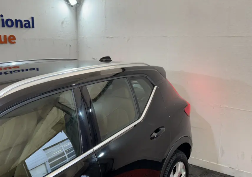 Vue 3/4 arrière droite du Volvo XC40 noir, mettant en valeur la ligne de toit et les vitres latérales chromées.