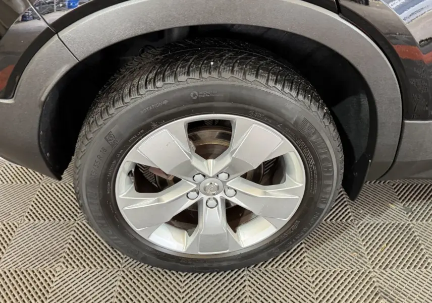 Gros plan sur la roue avant gauche avec jante argentée et pneu Michelin du Volvo XC40 noir Recharge T5 262 DCT7 Inscription.