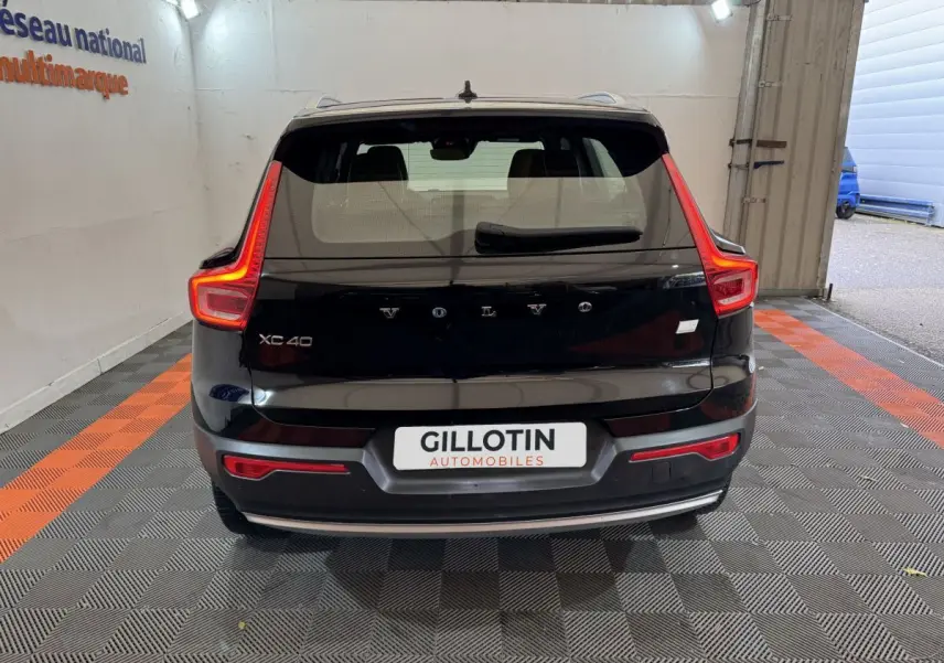Vue arrière d’un Volvo XC40 noir avec feux arrière en forme de L et logo Volvo visible sur le hayon.