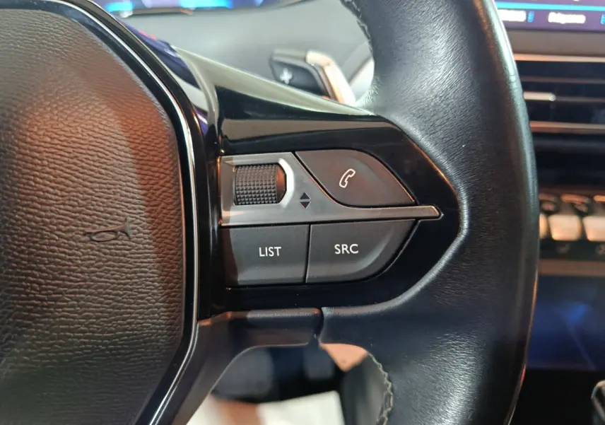 Gros plan sur les commandes gauche du volant cuir noir du Peugeot 3008 marron, avec boutons LIST et SRC visibles.