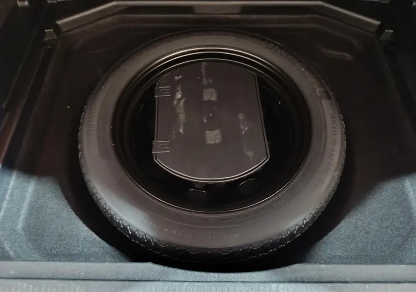 Gros plan sur la roue de secours noire dans le coffre du Peugeot 3008 marron, vue de dessus.