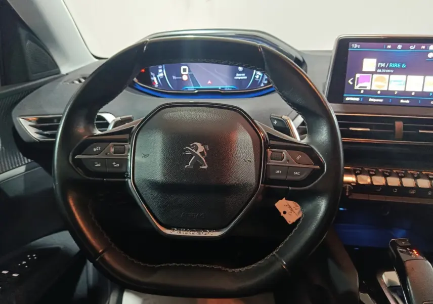 Vue intérieure centrée sur le volant cuir noir du Peugeot 3008 2019 avec tableau de bord digital et écran tactile.