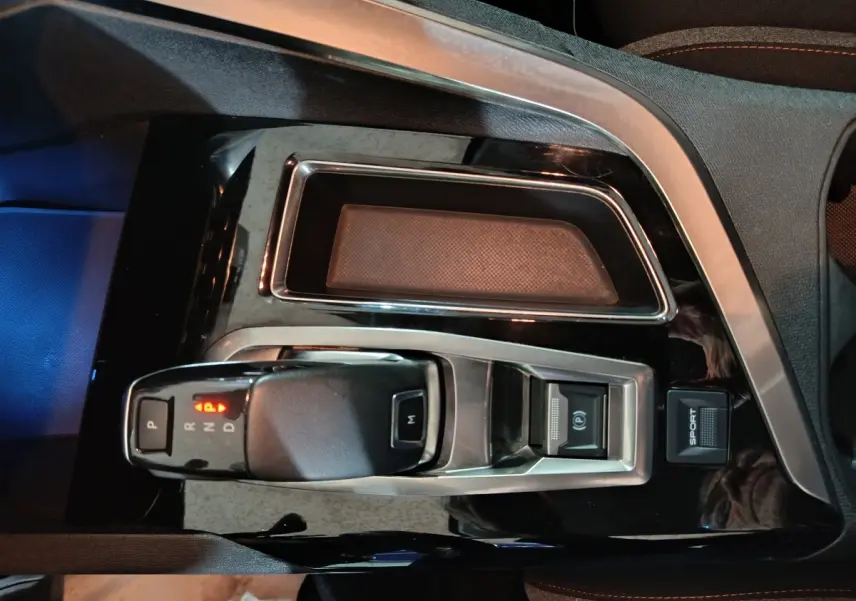 Vue plongeante sur la console centrale noire du Peugeot 3008 marron, avec levier de vitesse automatique et bouton Sport.