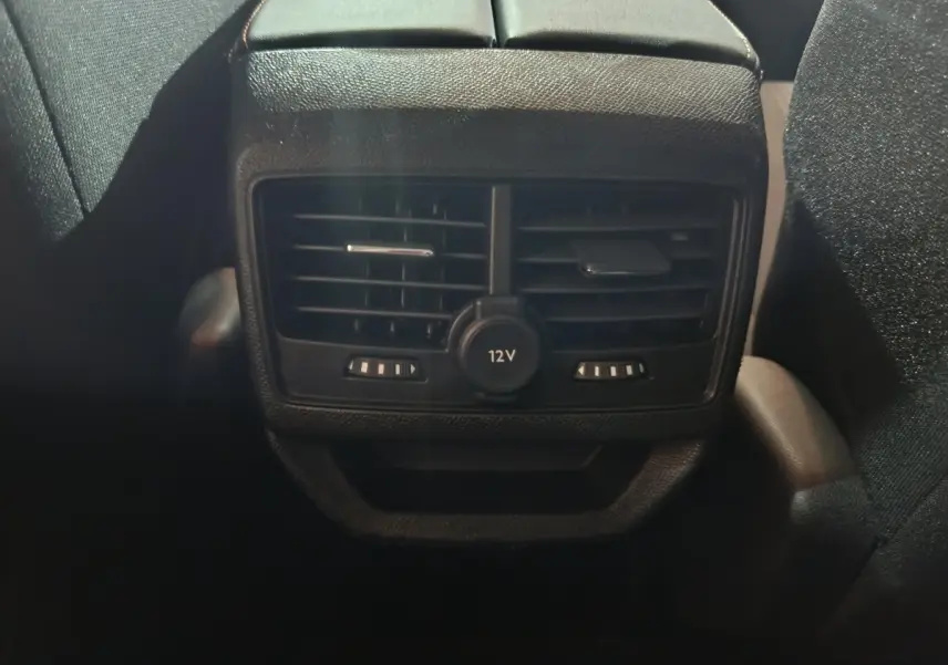Vue rapprochée des aérateurs arrière noirs et prise 12V du Peugeot 3008 marron, côté intérieur passagers arrière.