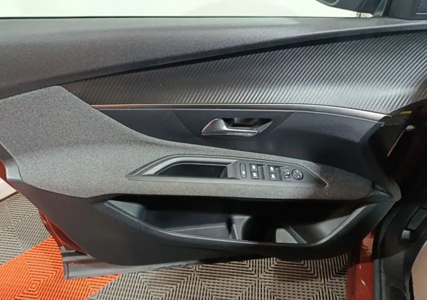 Vue intérieure du panneau de porte côté conducteur de la Peugeot 3008 marron, avec commandes électriques des vitres et rétroviseurs.