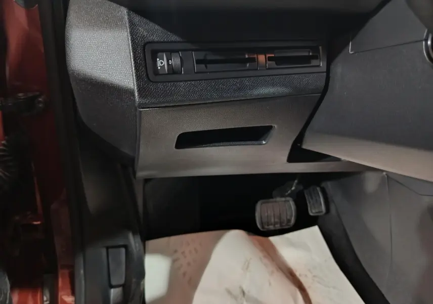 Vue intérieure côté conducteur du Peugeot 3008 marron, montrant les pédales et commandes d'éclairage sous le tableau de bord.