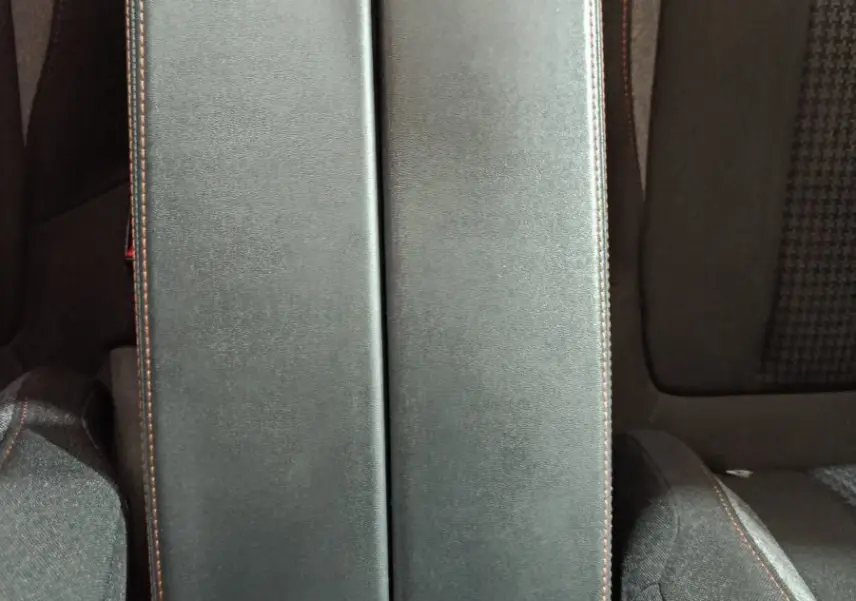 Vue plongeante sur l'accoudoir central noir avec surpiqûres marron entre les sièges avant du Peugeot 3008 marron.