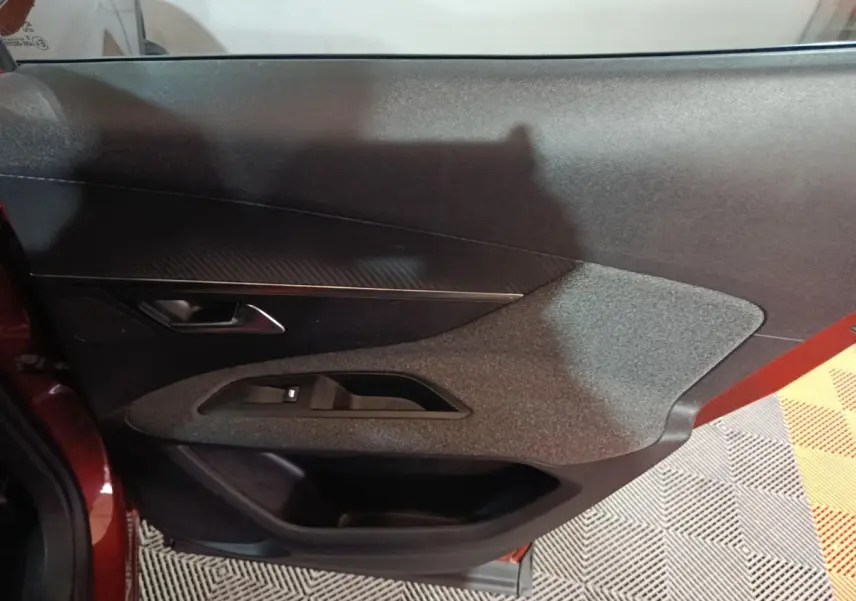 Vue intérieure côté gauche de la porte avant marron du Peugeot 3008 avec commandes de vitres et poignée intégrée.