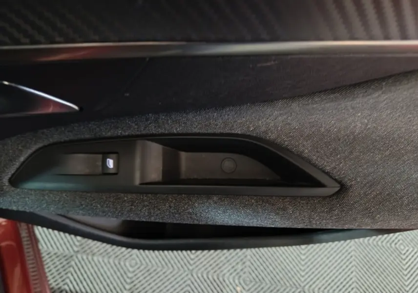 Gros plan sur la poignée intérieure et commande de vitre électrique côté gauche d’une Peugeot 3008 marron.
