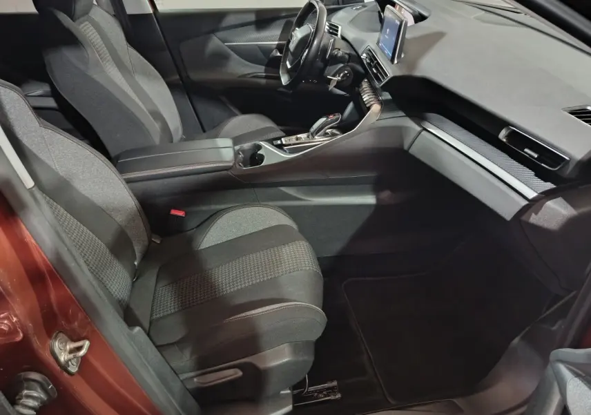 Vue intérieure côté conducteur du Peugeot 3008 marron, mettant en valeur les sièges tissu, le volant cuir multifonctions et l’écran tactile central.