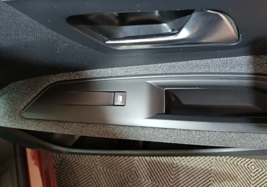 Détail de la commande de lève-vitre côté conducteur sur la porte intérieure d’un Peugeot 3008 marron.