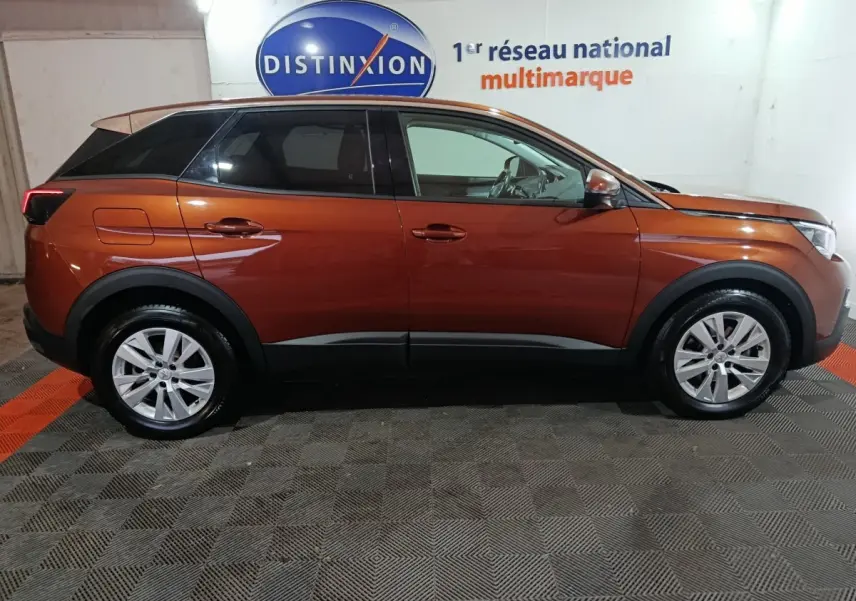 Vue de profil côté gauche d'un Peugeot 3008 marron 2019 avec toit noir et jantes alliage en intérieur showroom.