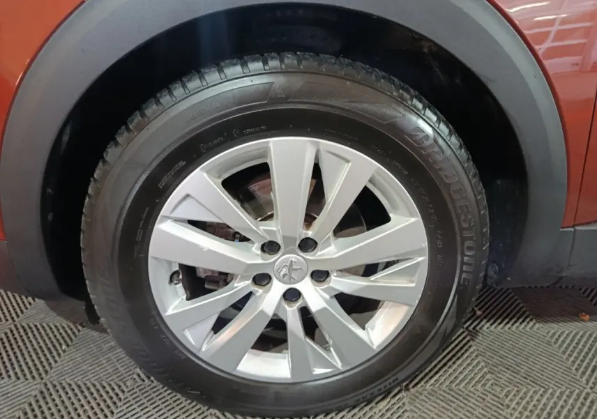 Gros plan sur la roue avant gauche avec jante argentée du Peugeot 3008 marron, version BlueHDi 130 de 2019.