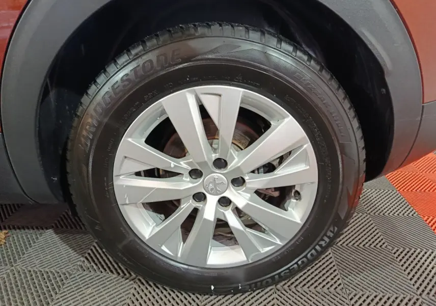 Gros plan sur la roue avant droite du Peugeot 3008 marron, mettant en valeur la jante argentée et le pneu Bridgestone.