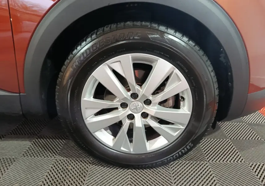 Gros plan sur la roue avant gauche d’un Peugeot 3008 marron, avec jante alliage argentée et pneu Bridgestone.