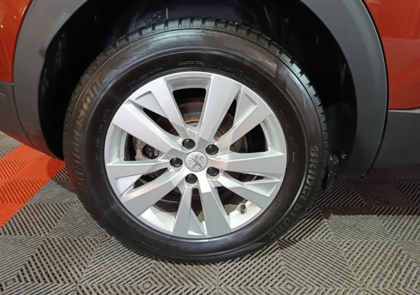 Gros plan sur la roue avant droite d’un Peugeot 3008 marron, jante alliage argentée avec logo lion central.