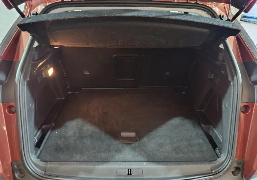 Coffre ouvert vu de l'arrière d'un Peugeot 3008 marron, montrant un espace de chargement propre et spacieux.