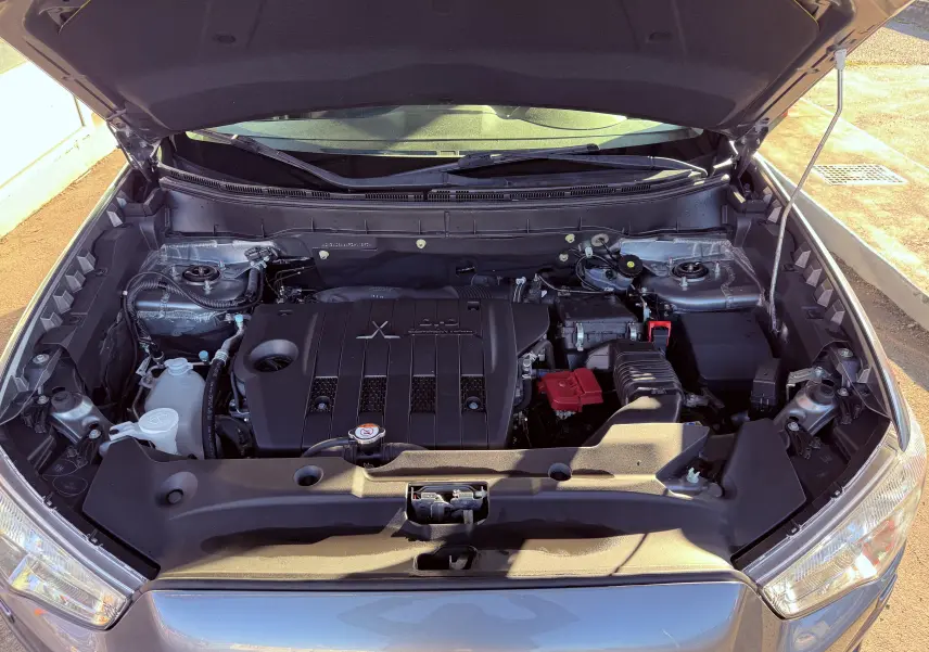 Vue plongeante sur le moteur diesel gris d'un Mitsubishi ASX 2015 avec capot ouvert au soleil.