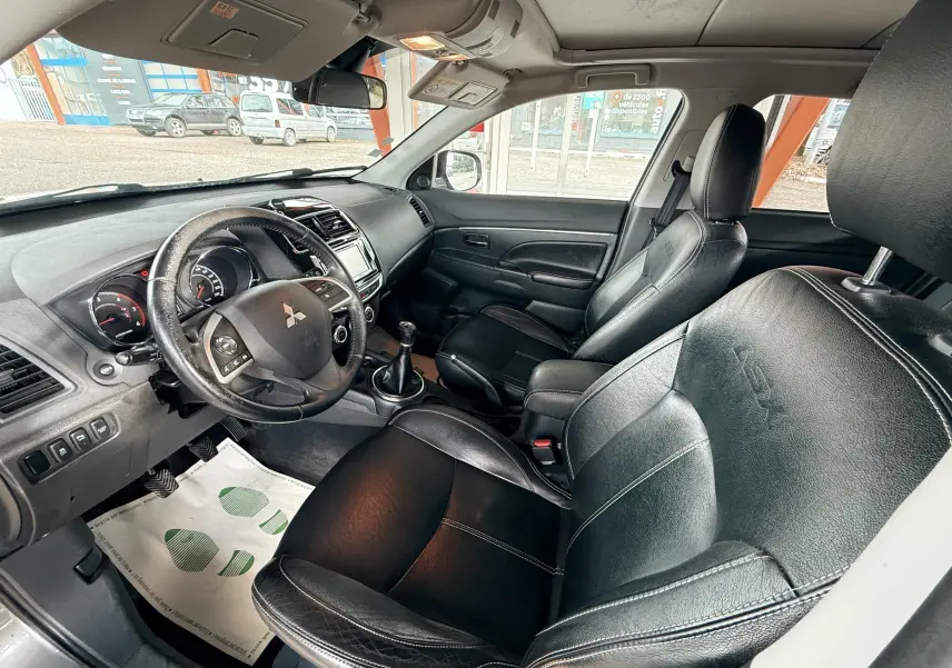 Vue intérieure côté conducteur du Mitsubishi ASX 2015, sièges en cuir noir et tableau de bord avec volant multifonction.