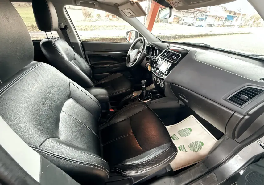 Vue intérieure côté conducteur du Mitsubishi ASX 2015, sièges cuir noir avec logo ASX, tableau de bord et volant visibles.