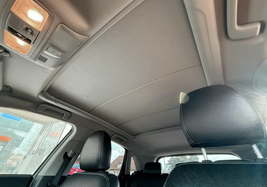 Vue intérieure du toit et des sièges avant en cuir noir avec surpiqûres blanches du Mitsubishi ASX gris de 2015.