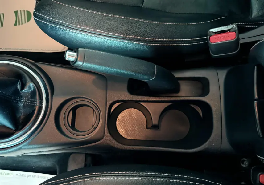 Vue plongeante sur la console centrale noire du Mitsubishi ASX 2015, avec frein à main et porte-gobelets.