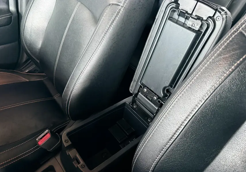 Vue rapprochée de l’intérieur du Mitsubishi ASX 2015 montrant l’accoudoir central en cuir noir ouvert entre les sièges avant.