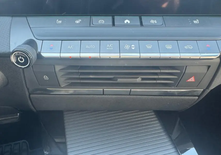 Vue rapprochée de la console centrale noire de l’Opel Astra 2024, avec commandes climatisation et boutons fonctionnels.