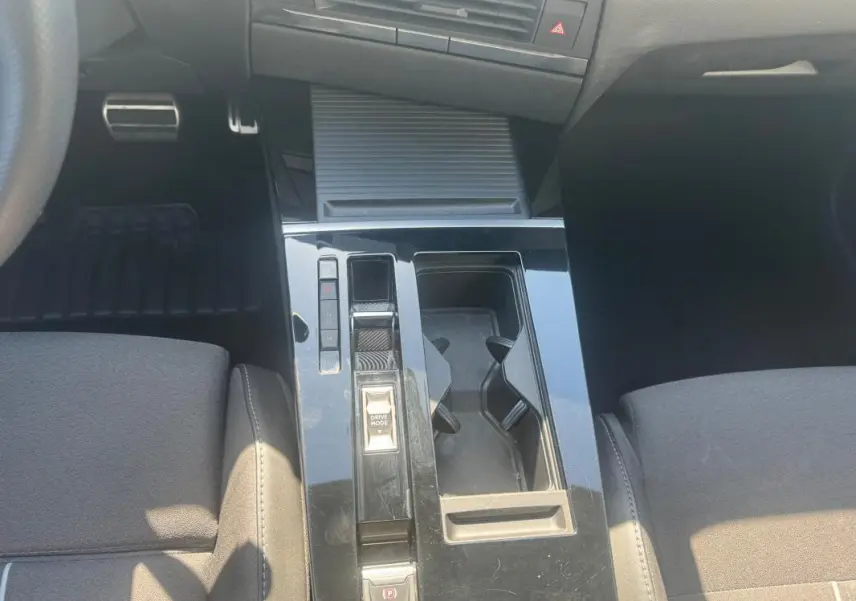Vue intérieure centrée sur la console centrale noire de l'Opel Astra 2024 avec commandes de boîte auto et porte-gobelets.