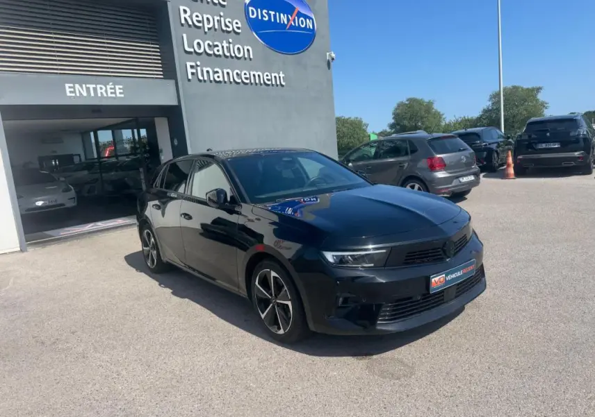 Opel Astra noire vue en 3/4 avant droit, avec jantes alliage 17 pouces et calandre moderne, stationnée devant un bâtiment.