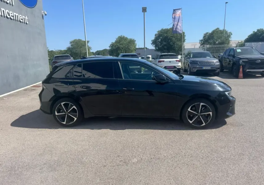 Opel Astra noire vue de profil côté gauche, avec jantes alliage 17 pouces et vitres surteintées.