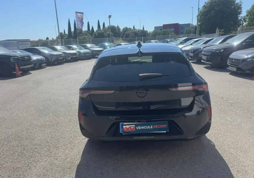 Vue arrière d'une Opel Astra noire 2024 avec vitres surteintées et feux arrière LED fins sur parking.