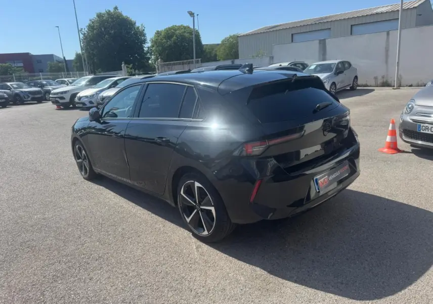Opel Astra noire vue 3/4 arrière droit, avec vitres surteintées et jantes alliage 17 pouces.