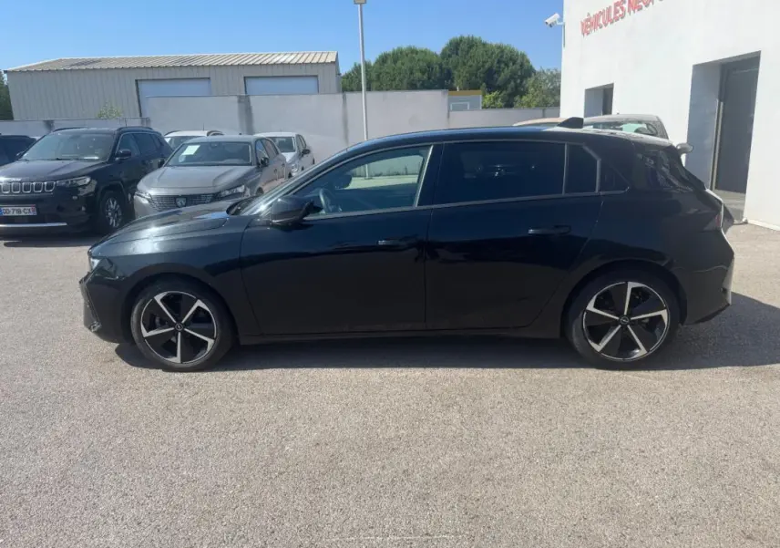 Opel Astra noire vue de profil côté gauche, avec jantes alliage 17 pouces et vitres surteintées.