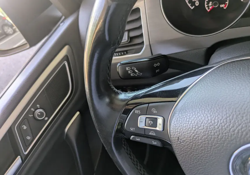 Gros plan sur le volant noir et la commande de régulateur de vitesse côté gauche du Volkswagen Golf Sportsvan 2014.
