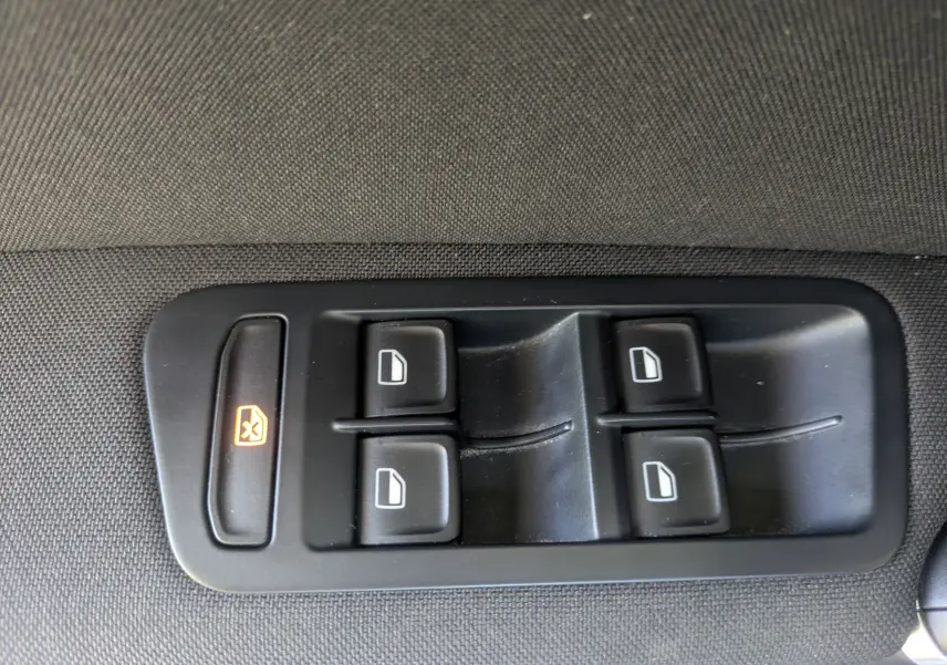 Boutons de commande des vitres électriques sur le panneau de porte intérieur d'une Volkswagen Golf Sportsvan noire.