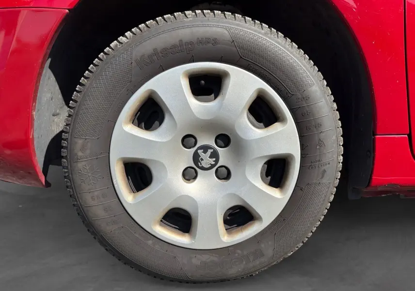 Gros plan sur la roue arrière droite d’un Peugeot Partner Tepee rouge de 2016, montrant le passage de roue et la carrosserie.