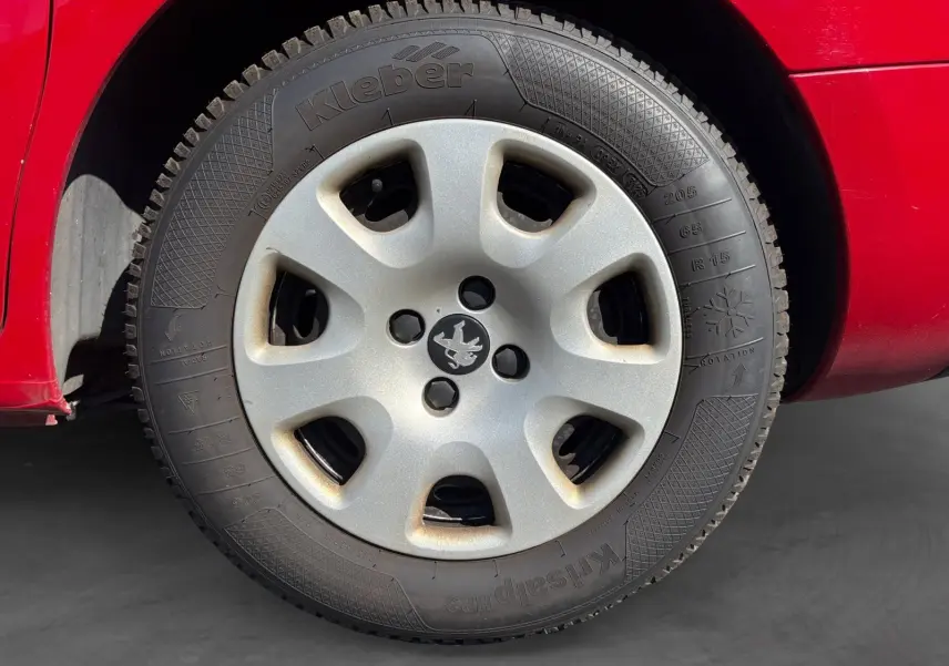Gros plan sur la roue arrière droite d’un Peugeot Partner Tepee rouge de 2016, mettant en valeur la carrosserie et le pneu.