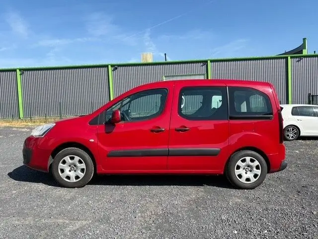 Vue de profil côté gauche d'un Peugeot Partner Tepee rouge de 2016 avec portes coulissantes et vitres électriques.