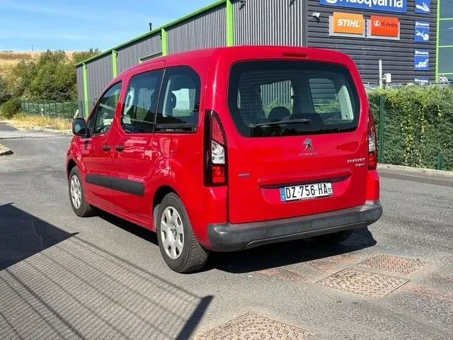 Vue 3/4 arrière droite d’un Peugeot Partner Tepee rouge de 2016 avec vitres arrière teintées et hayon fermé.