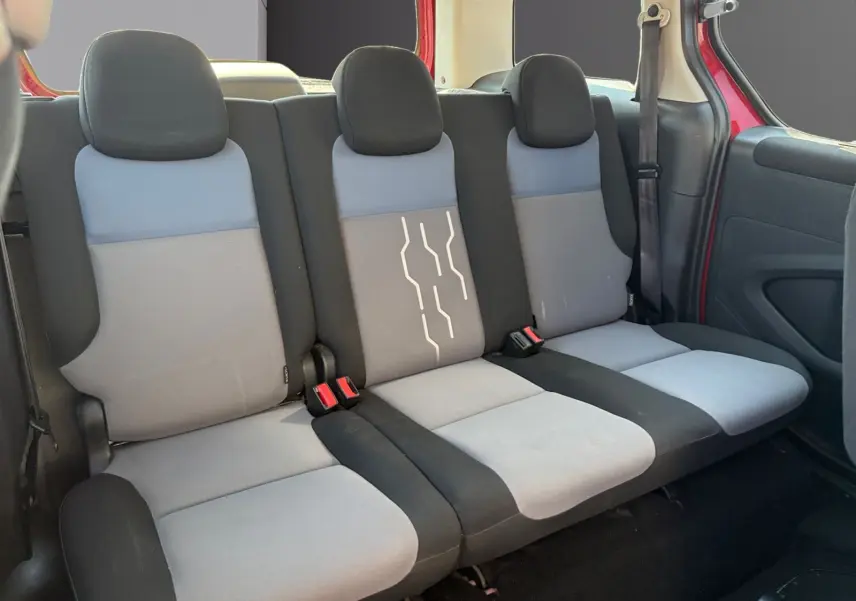Vue intérieure sur la banquette arrière grise et noire du Peugeot Partner Tepee rouge, avec ceinture de sécurité visible côté droit.