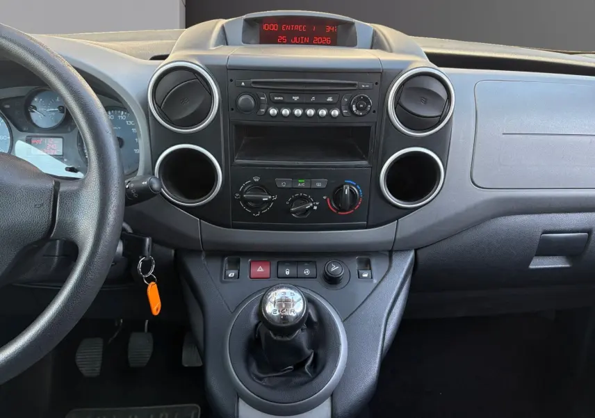 Vue intérieure centrée sur la console centrale et levier de vitesses manuelle du Peugeot Partner Tepee rouge de 2016.